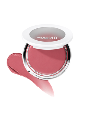 A round makeup compact with a white lid and silver rim, shown open with a pink pressed powder blush inside and a matching pink product smear in front. The lid is printed with the brand name 'by MARIO'.