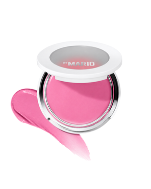 A round makeup compact with a white lid and silver rim, shown open with a bright pink pressed powder or cream blush. A matching pink smear is placed in front on a clean white background.