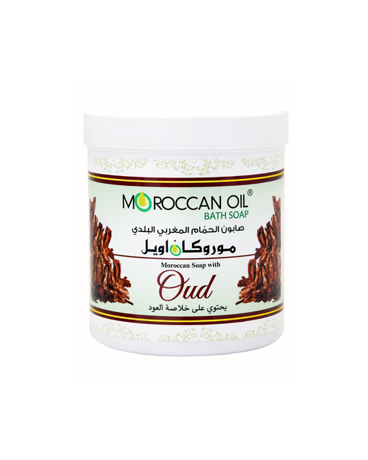 A white plastic tub of Moroccan Oil Bath Soap, variety 'Oud', featuring a white label with green and brown text and illustrations of dark brown oud wood.